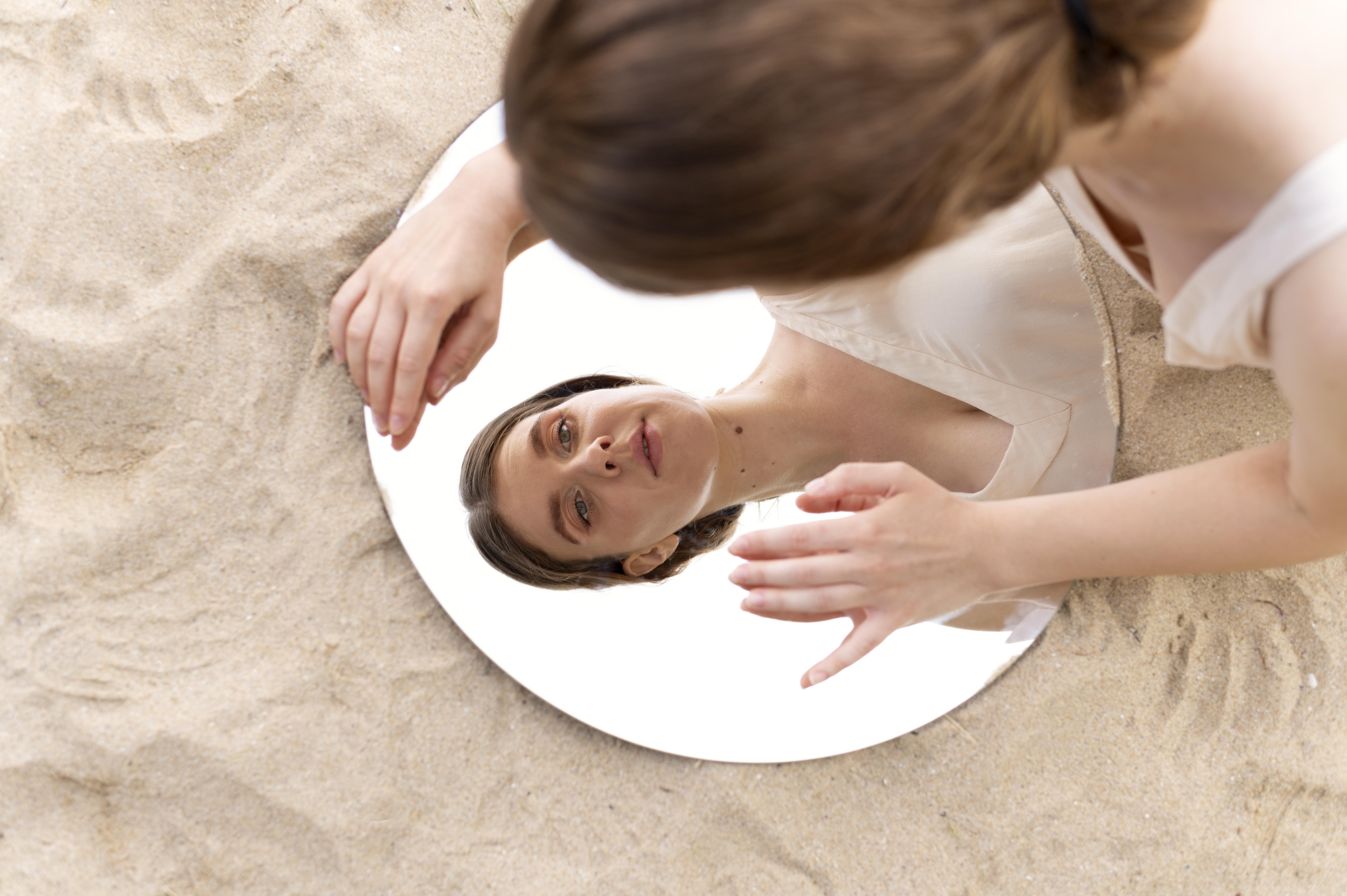 portrait-of-young-woman-posing-confidently-outdoors-with-round-mirror
